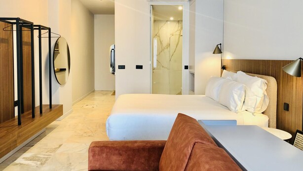 A modern hotel room with a bed, a sofa, a mirror, and an air conditioning unit. - Downtown 3C in Oporto (Porto)