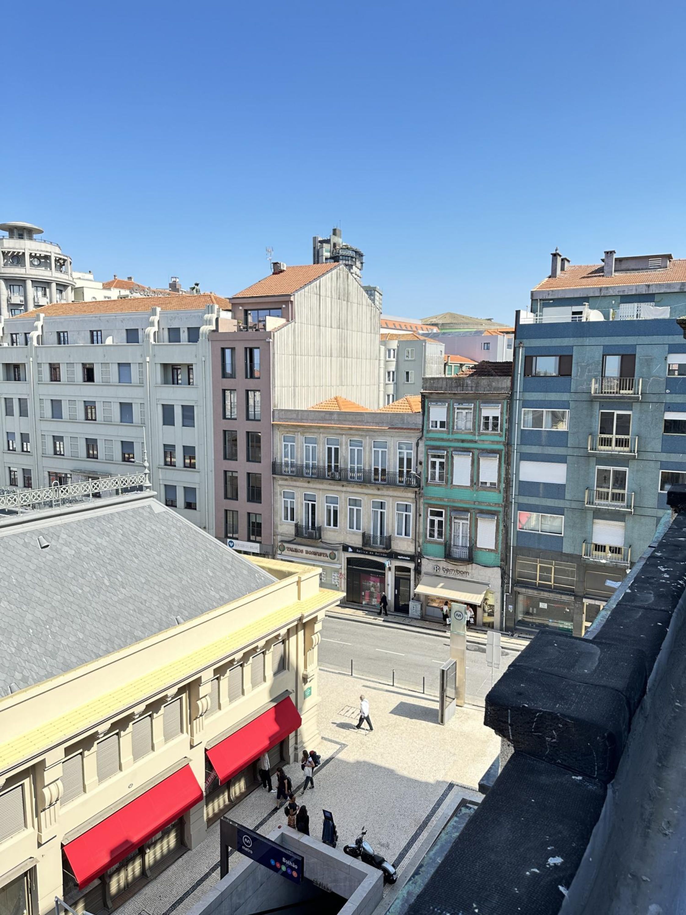 A cityscape with a variety of buildings, including a prominent white building with a grey roof and a red awning.