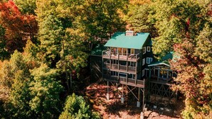 Eine mehrstöckige Hütte mit einem grünen Dach, umgeben von dichtem Wald.