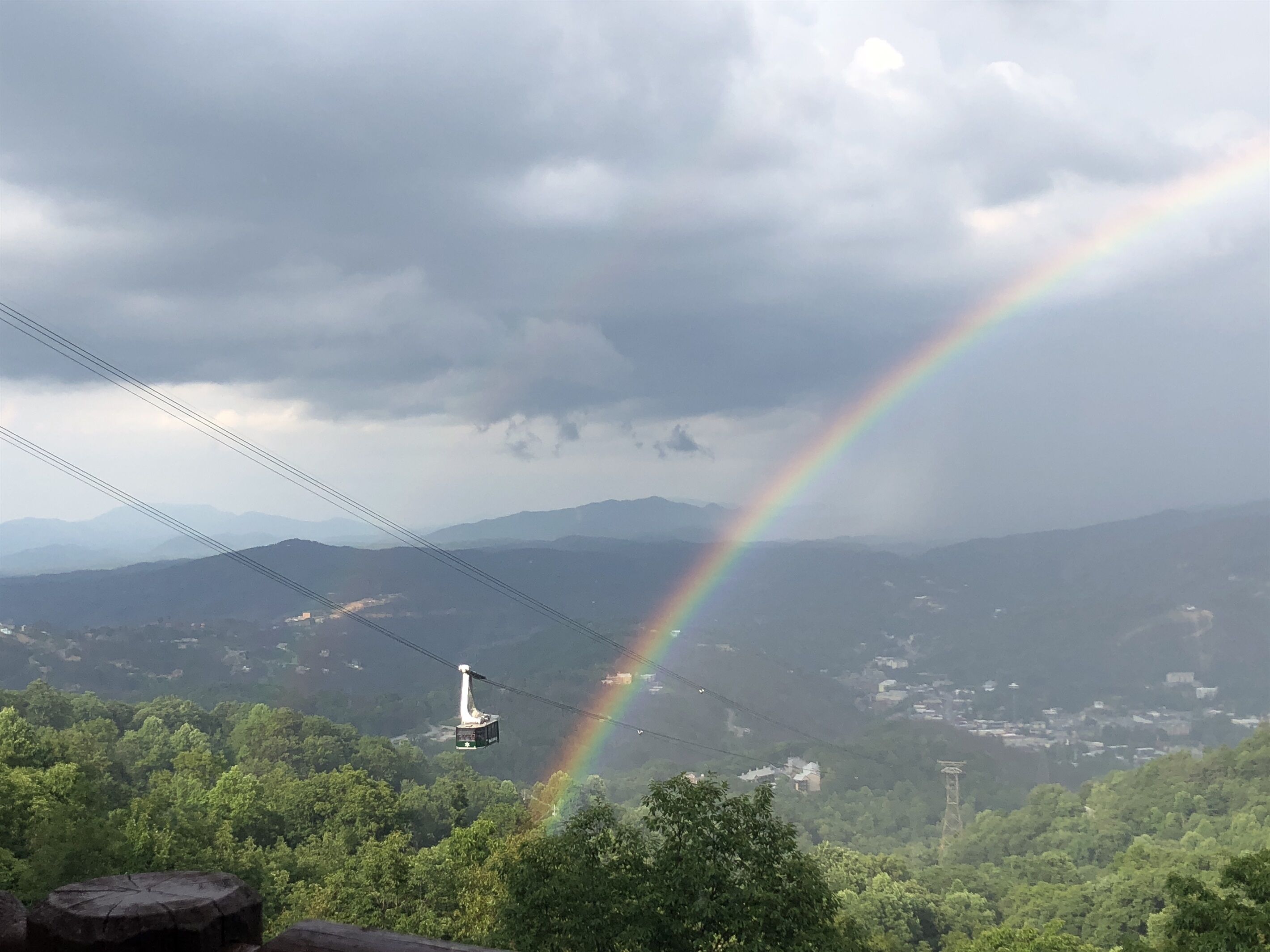 Un téléphérique avec un arc-en-ciel en arrière-plan.