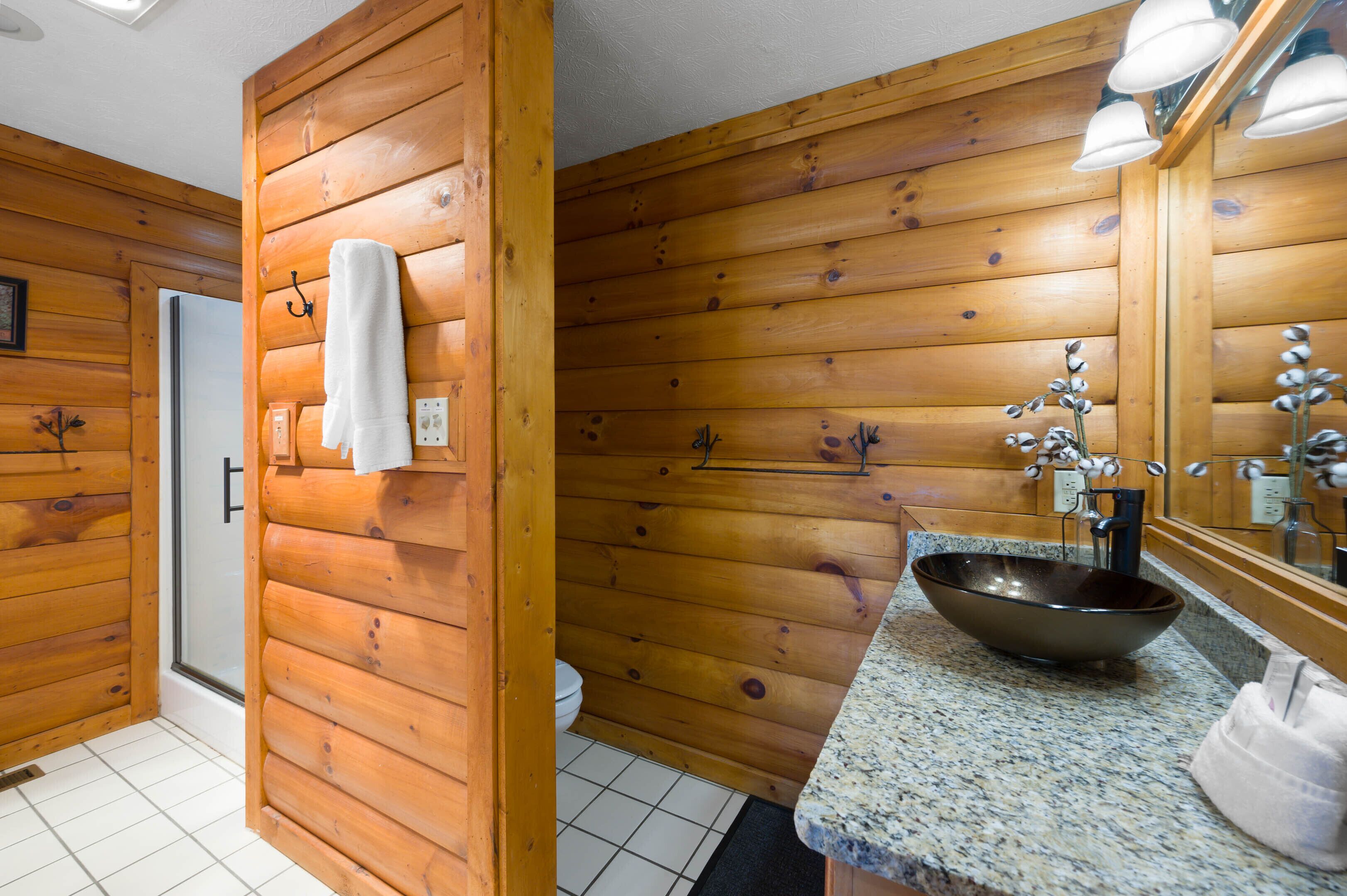 A wooden cabin bathroom with a sink, mirror, and towel rack.