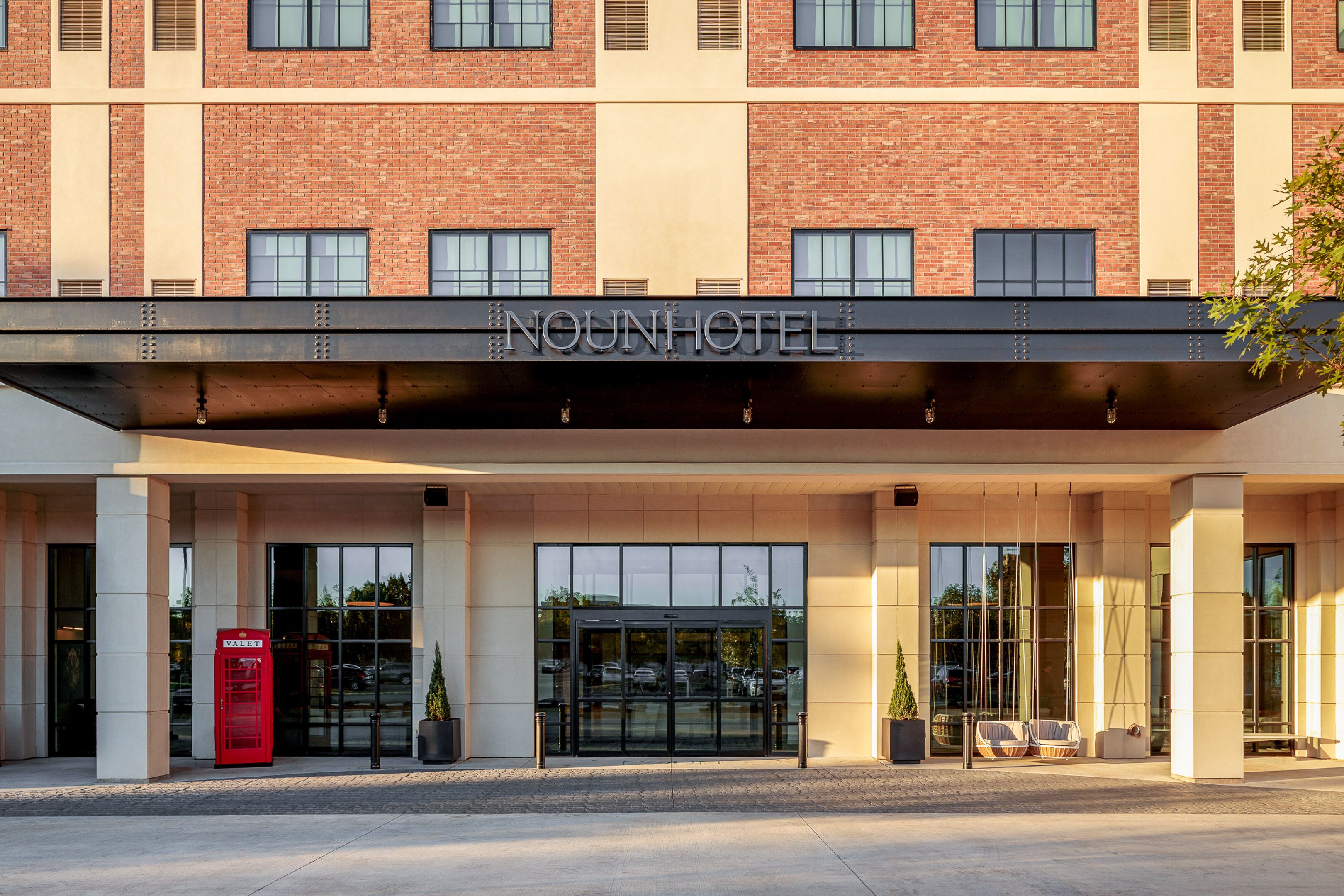 A hotel entrance with a brick facade, large glass doors, and a red telephone booth.