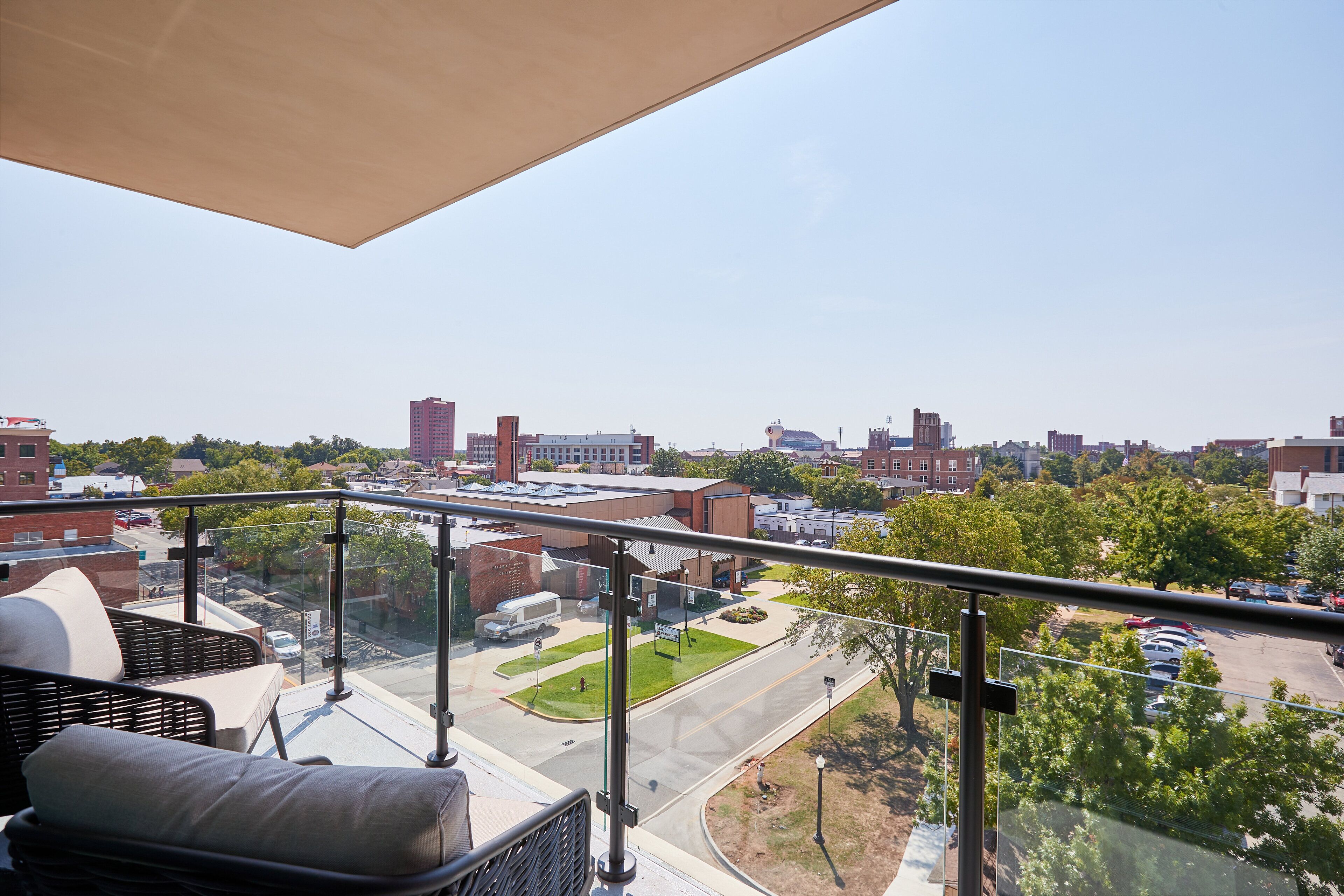 A balcony with a view of a cityscape, including buildings and a parking lot.