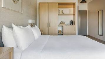 A hotel room with a large bed, a wardrobe, a bedside table with a lamp, and a mirror on the wall.