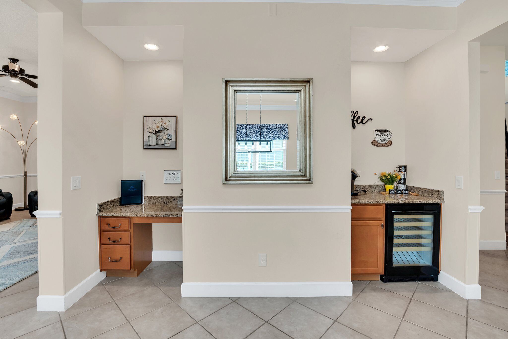 A kitchen with a built-in refrigerator, a window with blinds, and a countertop with a coffee machine.