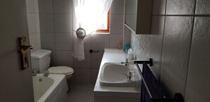 Une petite salle de bain compacte, équipée de toilettes, d’un lavabo et d’une fenêtre.