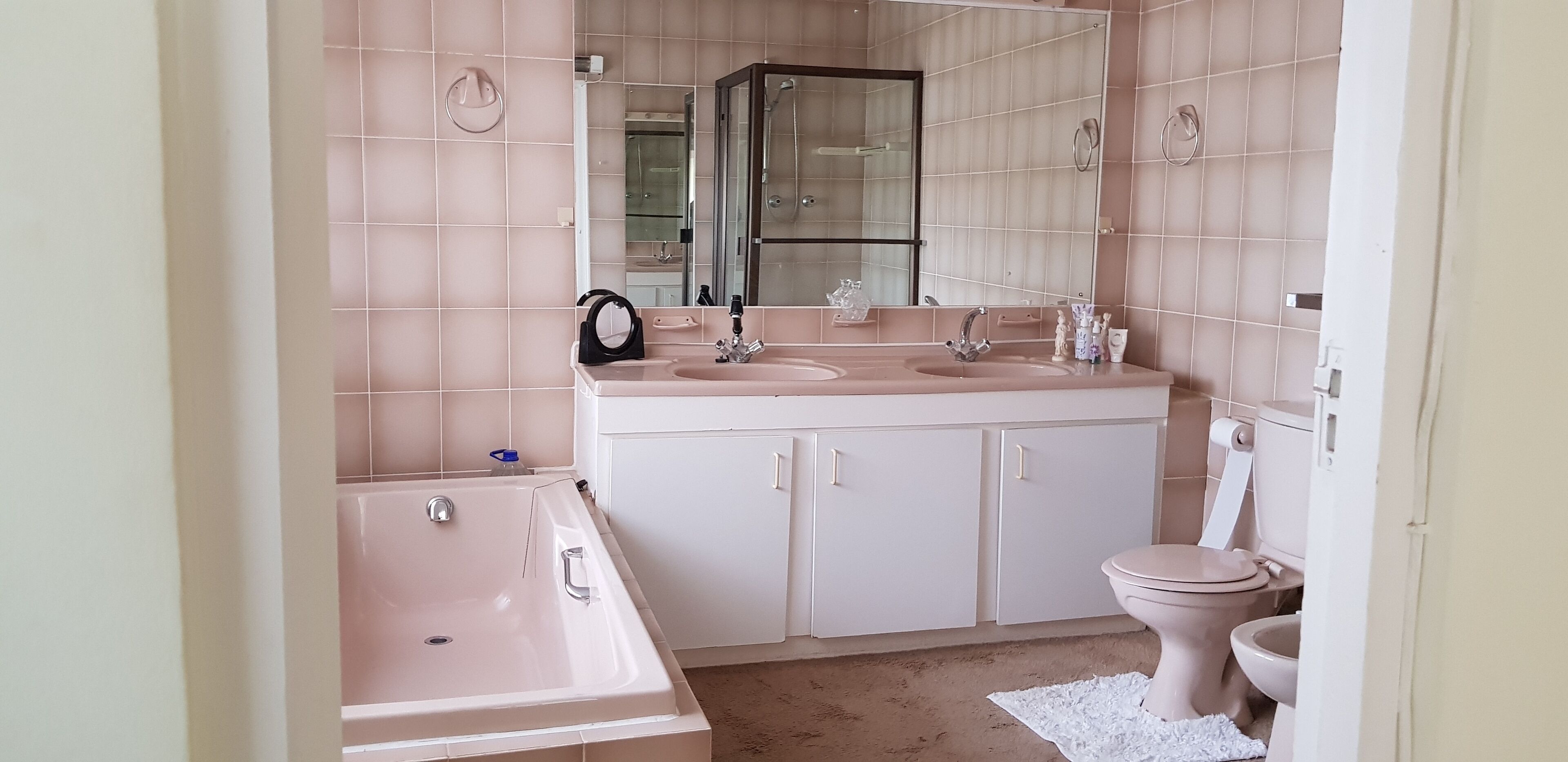 A bathroom with a bathtub, two sinks, a toilet, and a large mirror.