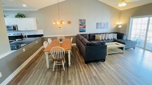A spacious living area with a dining table, sofa, and ceiling fan.