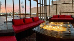 Un área de descanso moderna con asientos rojos y una chimenea central.