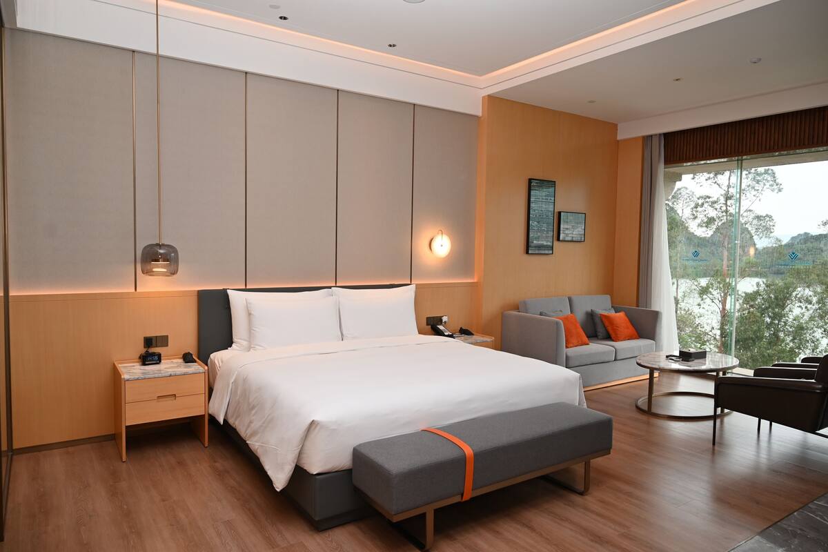 Una habitación de hotel moderna con una cama grande, mesitas de noche, un sofá y una mesa de centro.