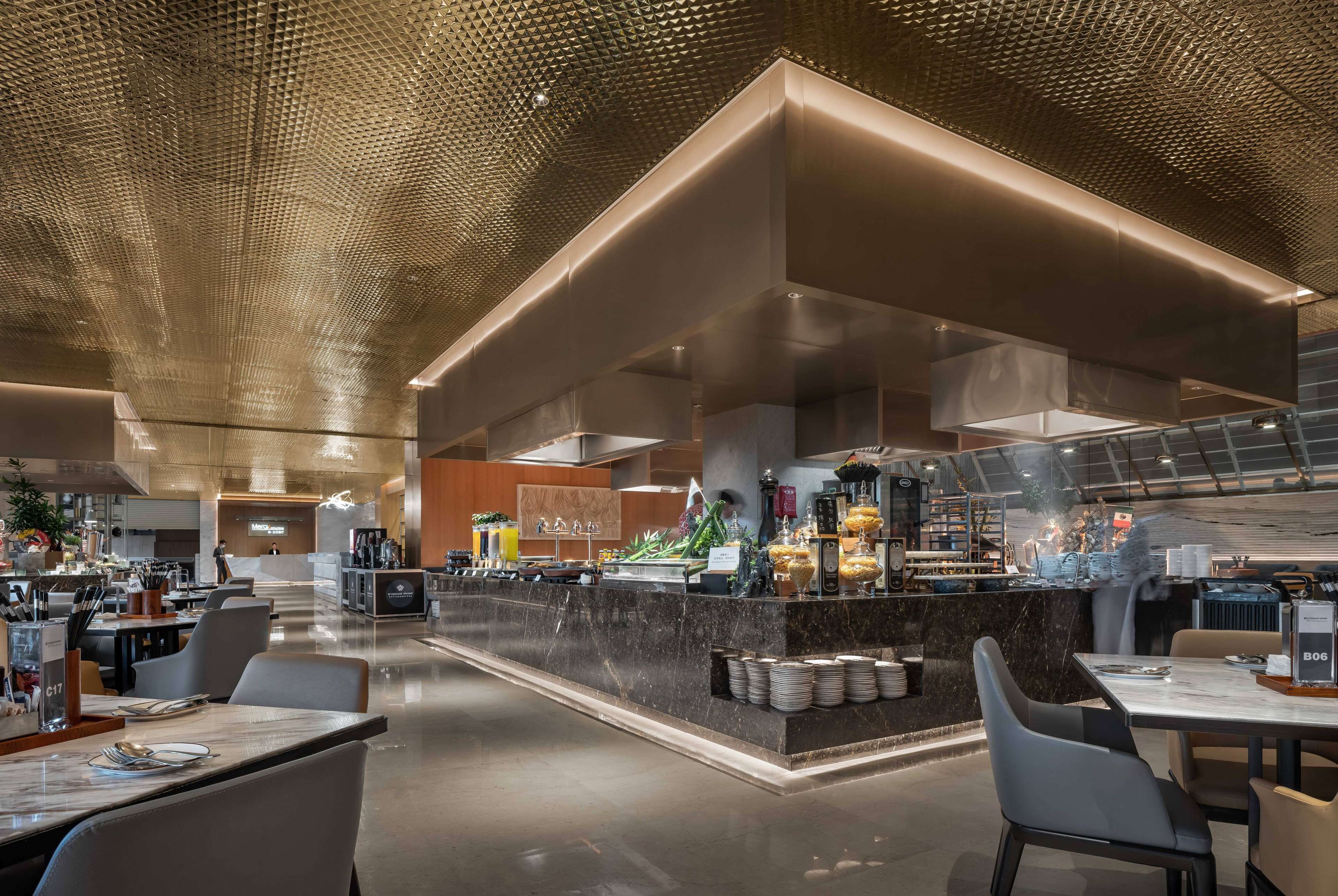 A modern restaurant with a central bar, seating area, and a polished ceiling.