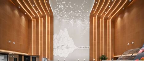 A spacious lobby with a modern design, featuring a large, illuminated wall art installation and a sleek, reflective floor.