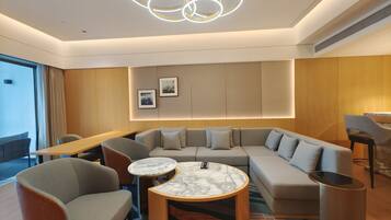 A modern living room with a sectional sofa, two armchairs, a marble coffee table, and a unique circular light fixture.