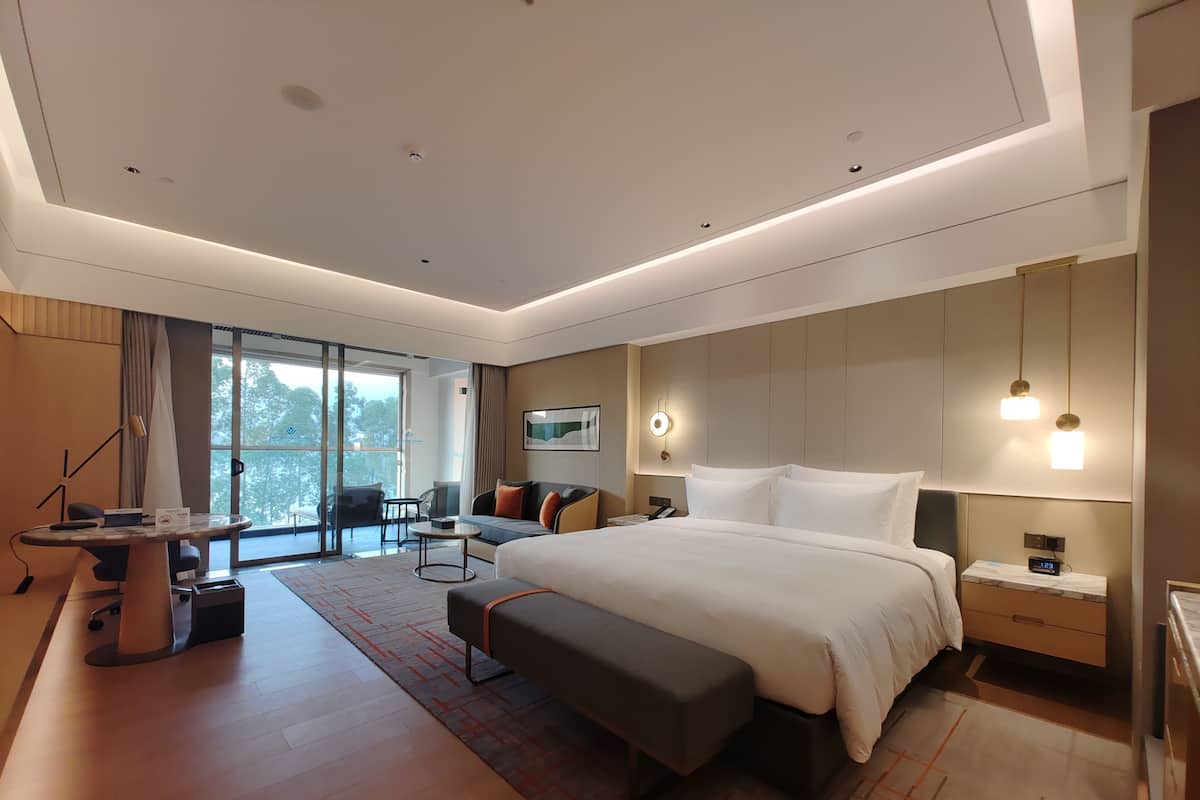 Una habitación de hotel moderna con una cama grande, un escritorio, un sofá y un área de comedor con vistas.