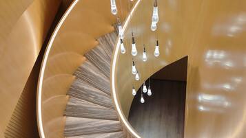 Una escalera de caracol con detalles de madera pulida e iluminación de cristal colgante.