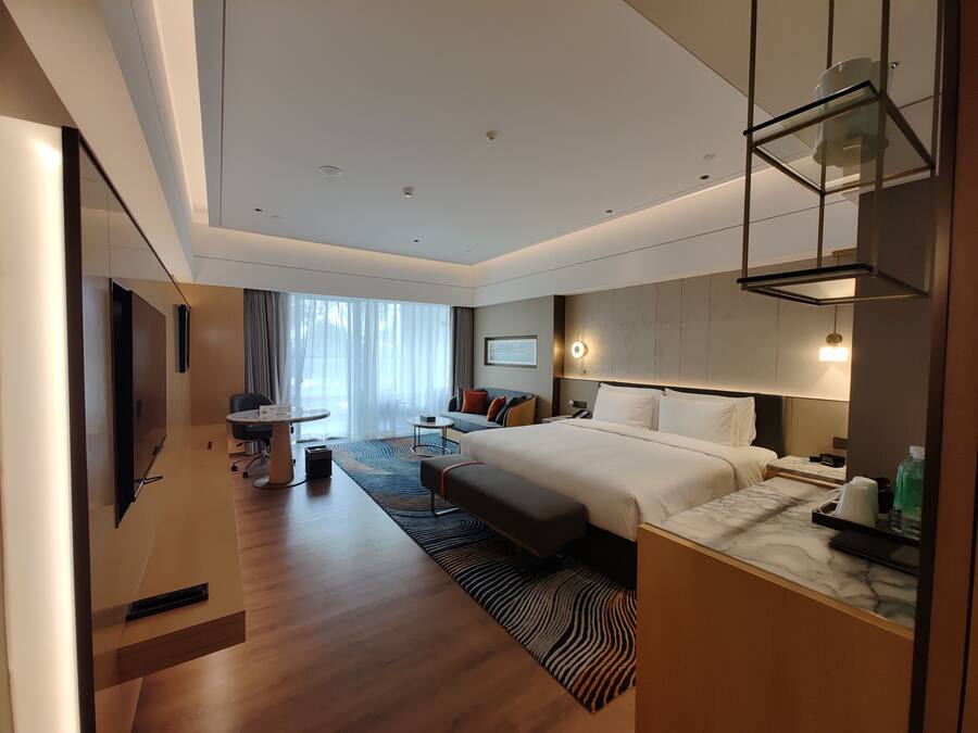 Una habitación de hotel moderna con una cama grande, un escritorio, una silla y vistas al exterior.