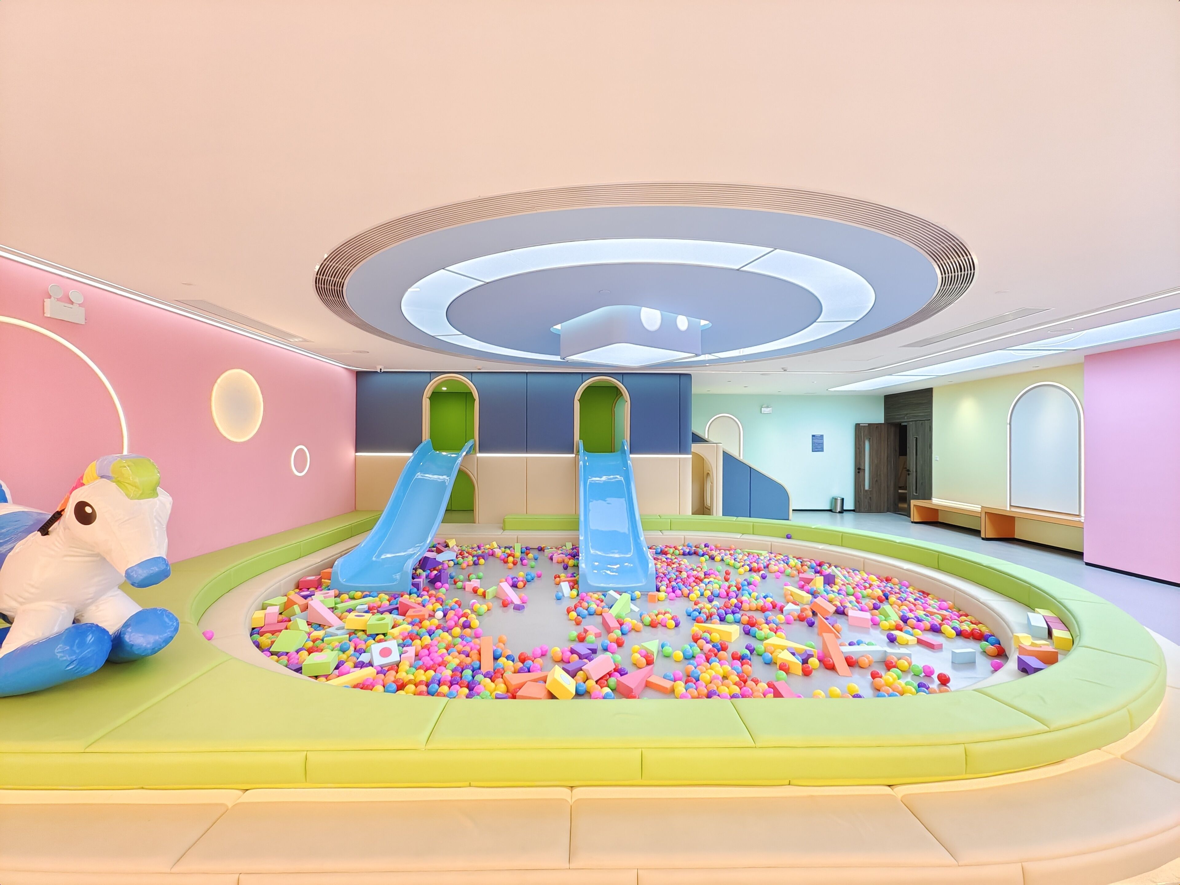 A children's play area with two slides and a ball pit filled with colorful balls.