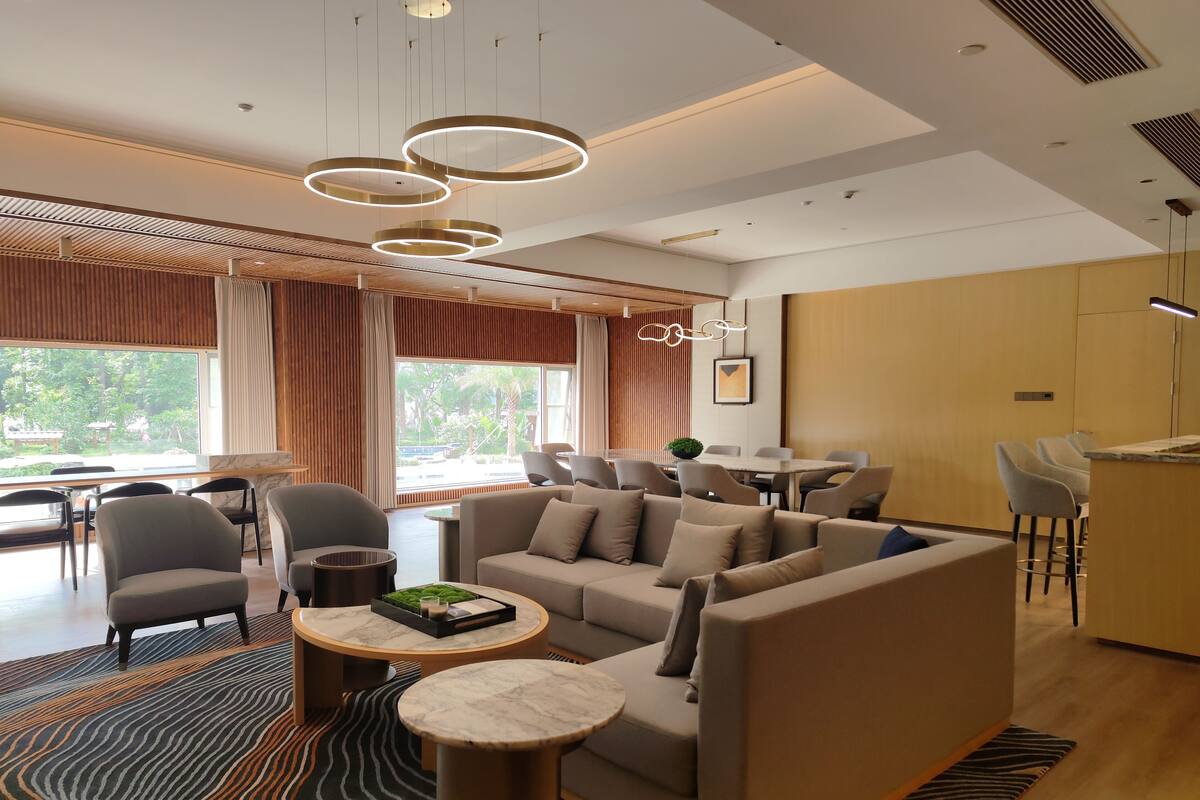 Un moderno hall de hotel con sofá, sillas, comedor y cocina.
