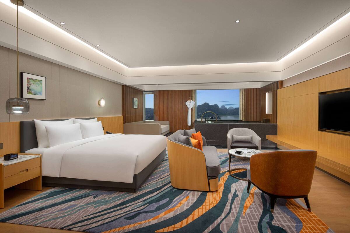 Una habitación de hotel moderna con una cama grande, un sofá, una silla, un escritorio y un televisor.
