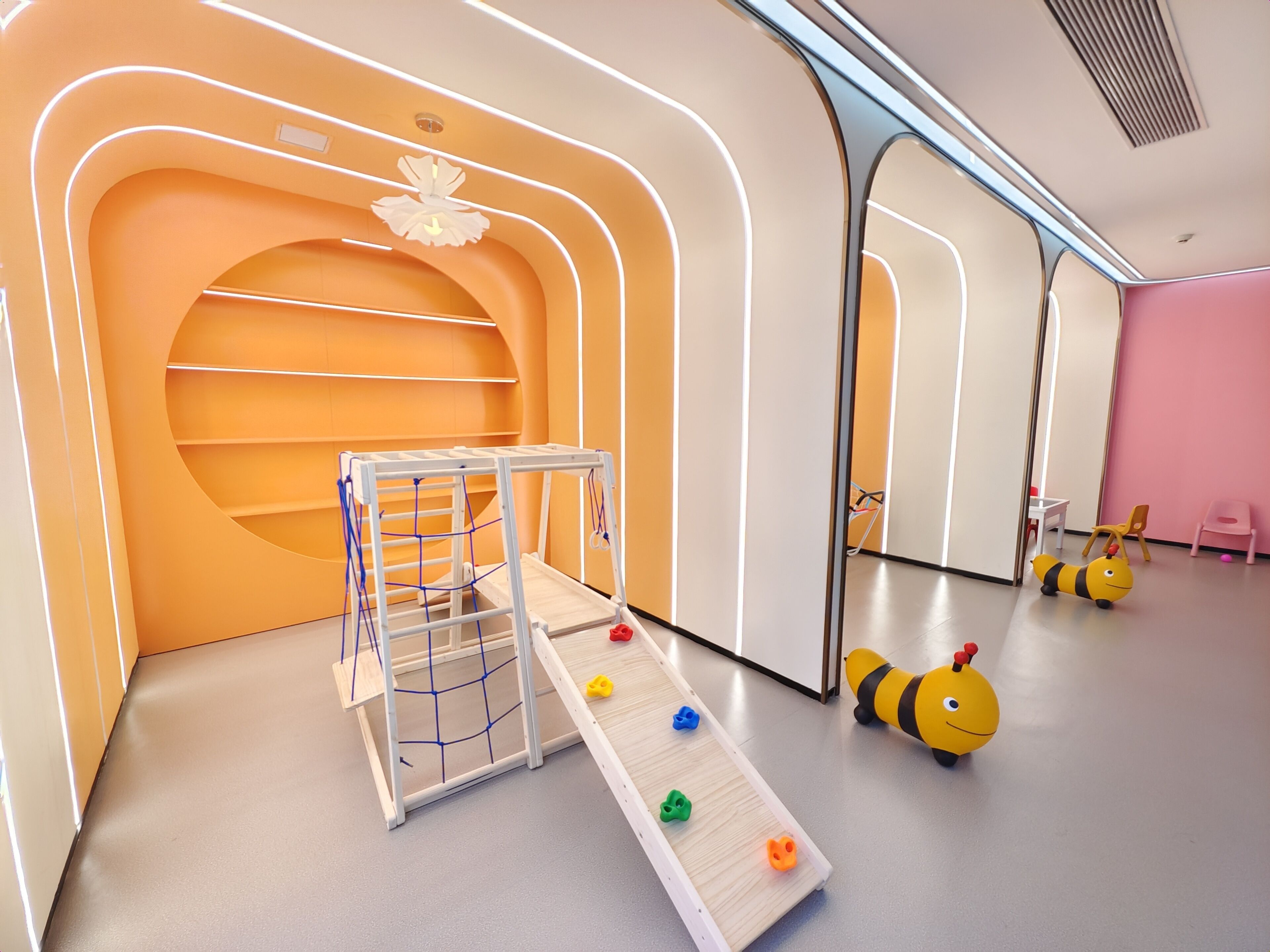 Un espace de jeux pour enfants avec un toboggan, des jouets et un mur recouvert de miroirs.