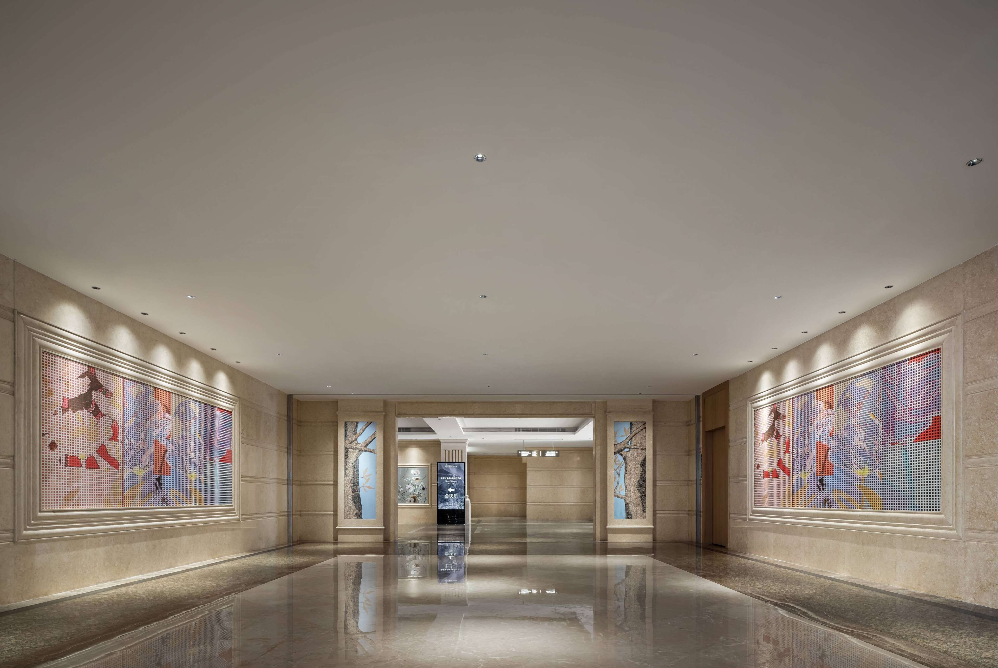 A spacious, modern lobby with a polished floor, large abstract wall art, and recessed lighting.