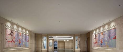 A spacious, modern lobby with a polished floor, large abstract wall art, and recessed lighting.