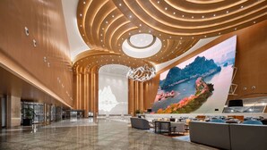 A spacious lobby with a modern design, featuring a large digital screen displaying scenic landscapes, a curved ceiling with integrated lighting, and a polished marble floor. - Wyndham Grand Zhaoqing Downtown (Zhaoqing)