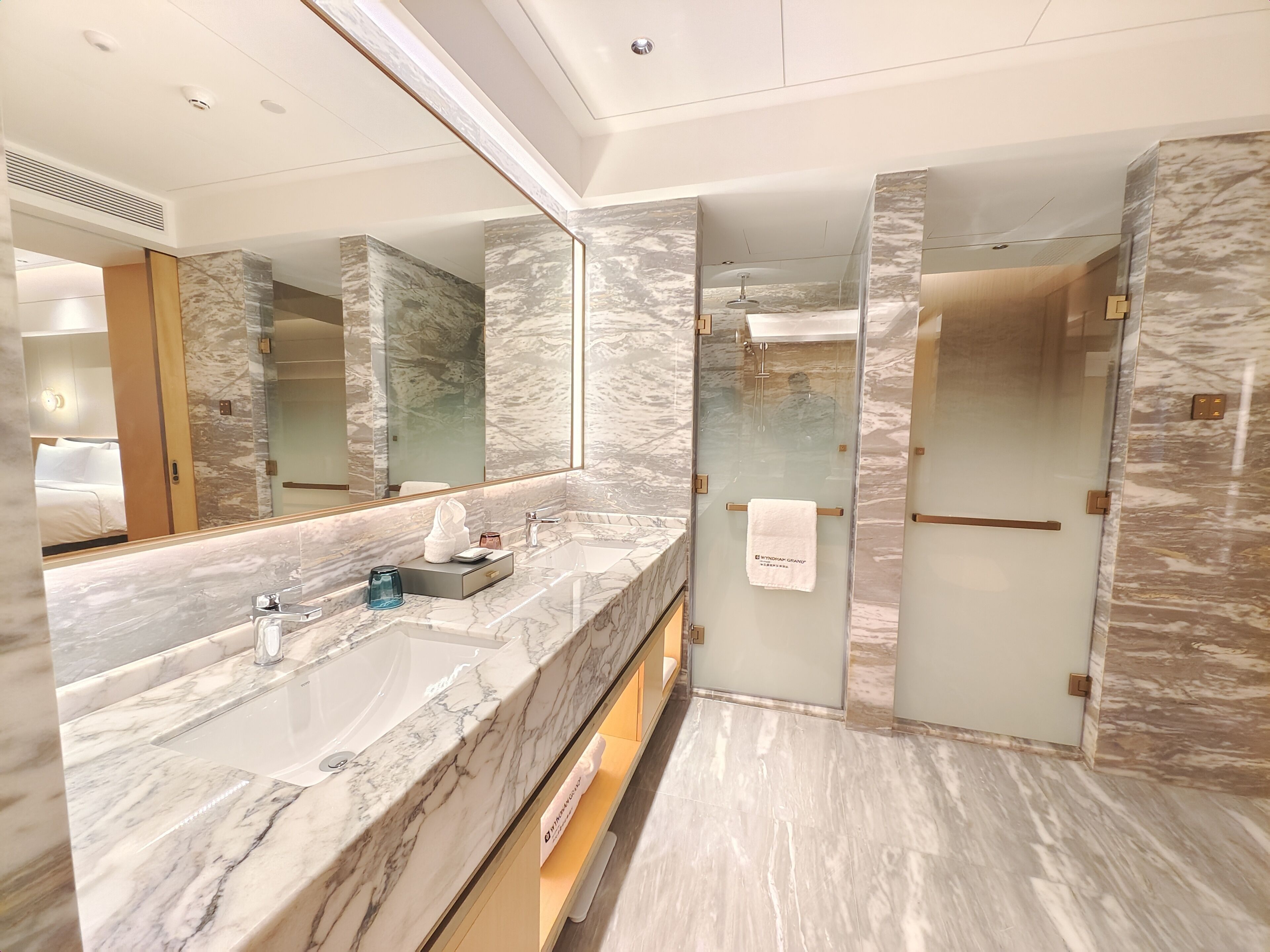 Un bagno moderno con un ampio lavabo in marmo, una doccia vetrata e un grande specchio.