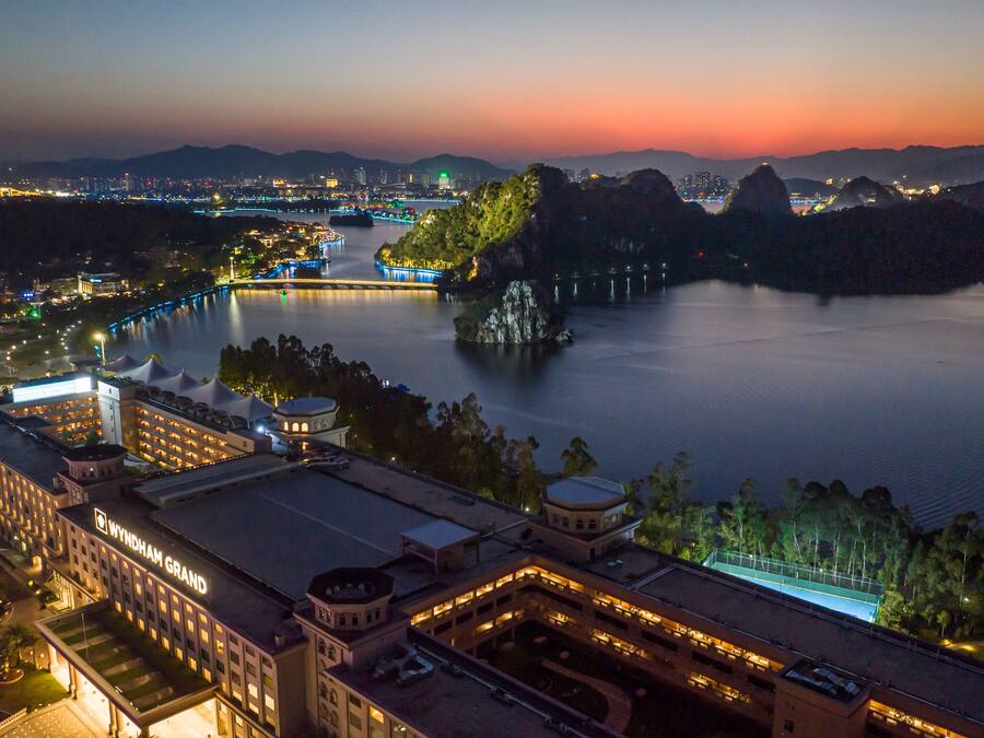 A hotel with a large building, a parking area, and a view of a river with a bridge.