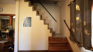 A staircase with a wooden handrail and carpeted steps, leading to a landing with a zebra-striped artwork.