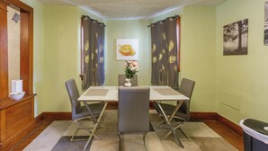 A conference room with a table, chairs, a vase with flowers, and a painting on the wall.