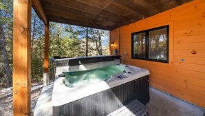 Un bain à remous dans un chalet en bois, avec une fenêtre donnant sur la forêt.