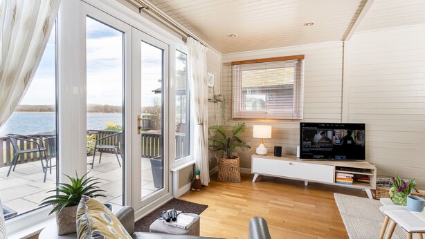Una sala de estar moderna con televisor, asientos y vistas al exterior.