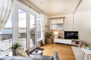 Una sala de estar moderna con televisor, asientos y vistas al exterior.