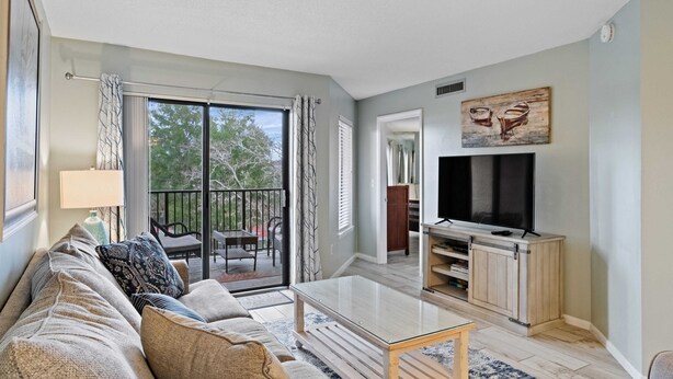 A living room with a sofa, coffee table, TV, and sliding glass doors leading to an outdoor area. - Beautiful Spacious Condo Overlooking Pool - walk to Beach and  Coligny Plaza ! (Hilton Head Island)