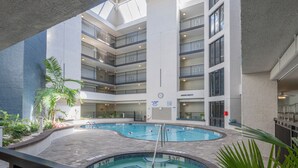 Piscina interior em vários níveis com piscina circular central, rodeada por varandas e plantas.