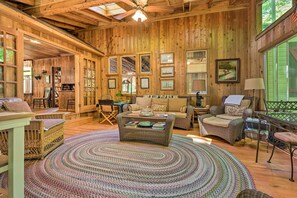 Relax in this inviting living room with a wicker sofa, armchair, and loveseat, surrounded by framed pictures and a large window.