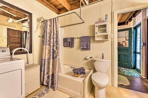 Ein Badezimmer mit Waschmaschine, Badewanne, Toilette und Duschvorhang.