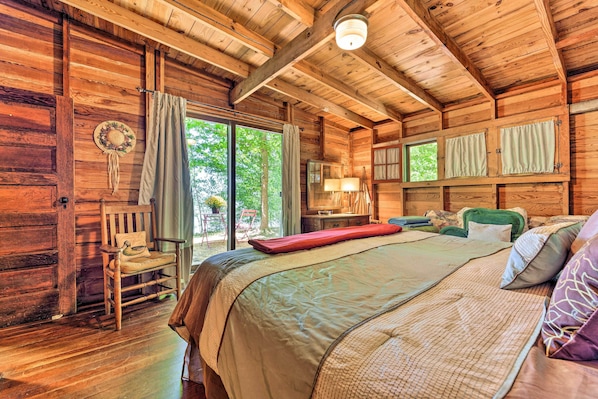 Relax in this charming bedroom with a large bed, wooden rocking chair, and a small table with a lamp.