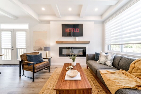 A modern living room with a fireplace, a mounted TV, and a cozy seating area.