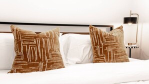 A bed with two patterned pillows and a white comforter.