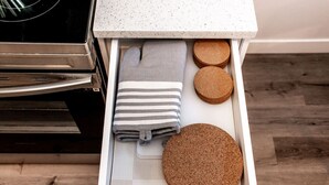 A kitchen drawer with a white countertop, a stainless steel oven, and a wooden floor.