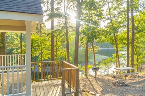 A wooden deck overlooking a lake surrounded by trees.