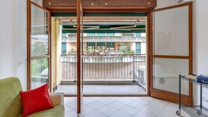 Una habitación con puerta corrediza de vidrio que da a un balcón con vistas a otros edificios.