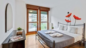Un dormitorio con una cama, un escritorio y una ventana con vistas a edificios.