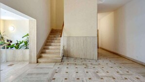 Un interior moderno con una escalera, paredes de colores claros y un suelo con estampado de espiga.