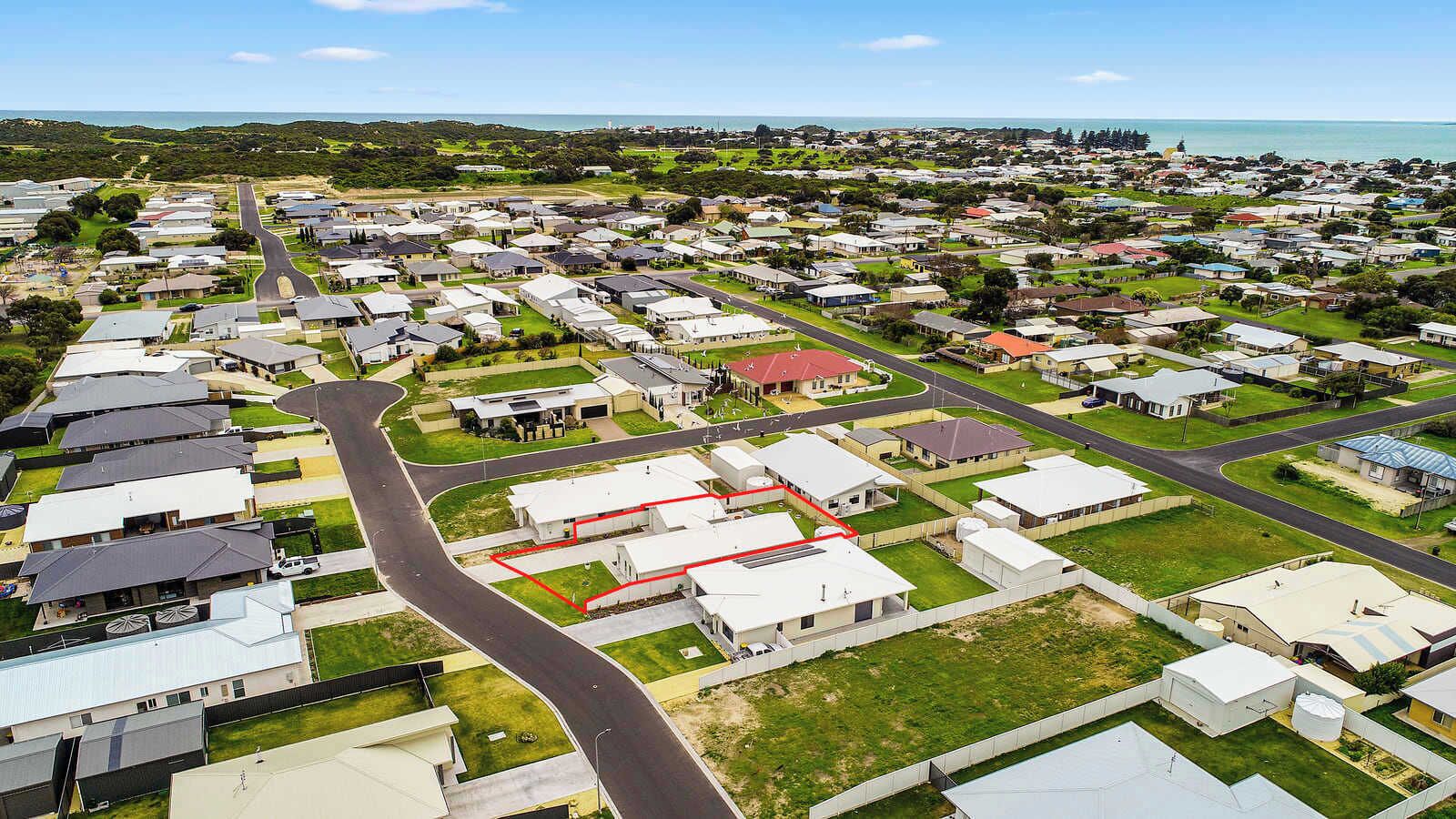 Vista aérea de una zona residencial con casas, caminos y un cuerpo de agua.