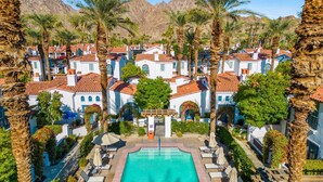 A resort with white buildings, a swimming pool, and palm trees. - SV112 Deluxe Spa Villa w/ Majestic Mountain Views (La Quinta)