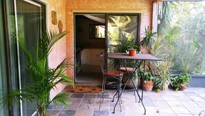 Een patio met een tafel en stoelen, omgeven door plantenpotten en uitzicht op de omgeving.