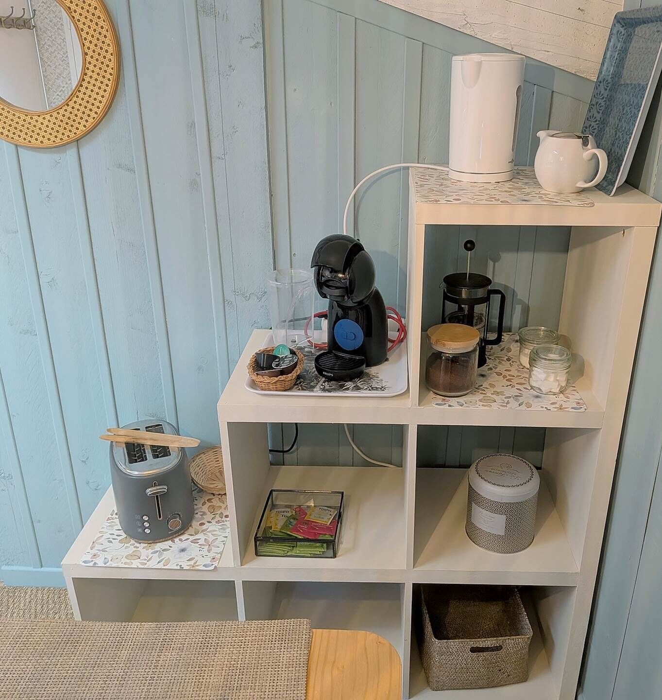 Eine Küchenzeile mit Kaffeemaschine, Toaster und verschiedenen Küchenutensilien auf Regalen.